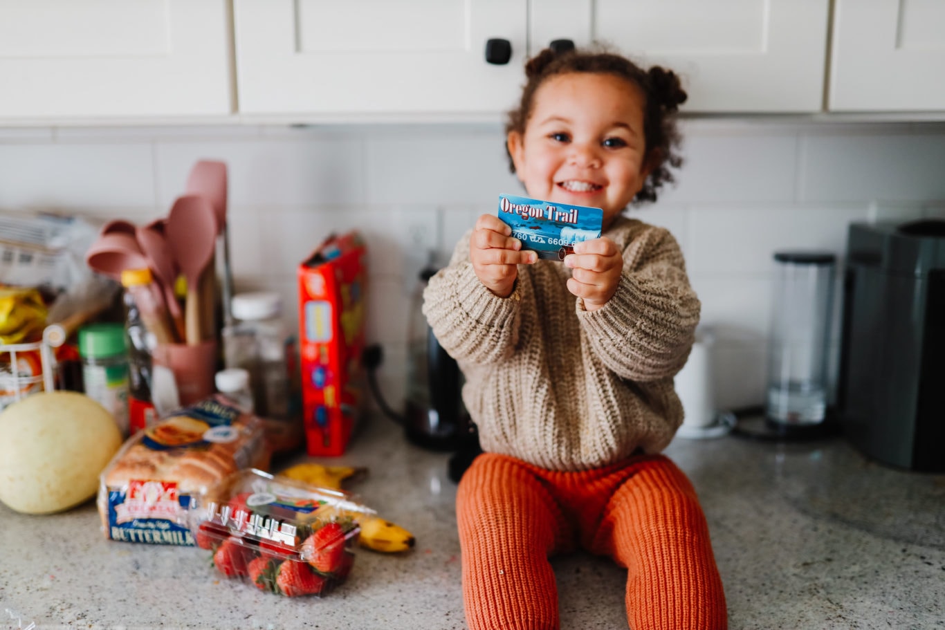 Smiling child holding an Oregon EBT card, symbolizing restored SNAP benefits and food access